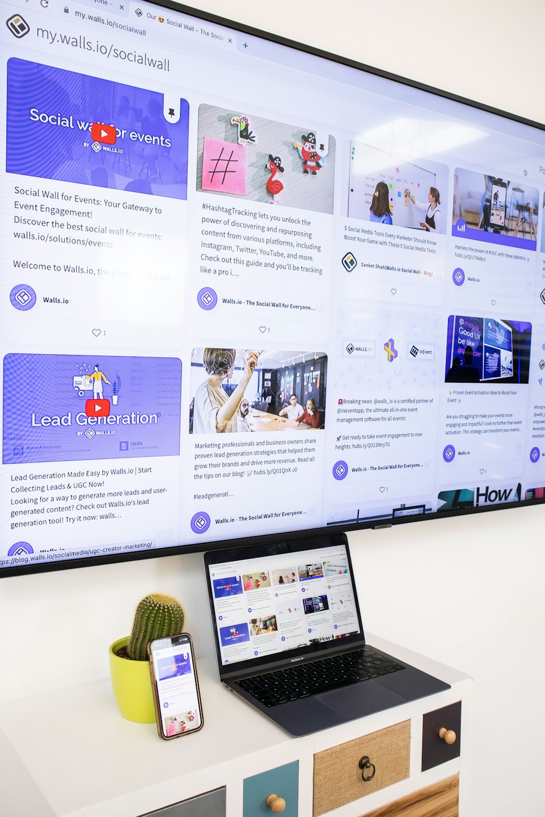A TV screen, a laptop and a smartphone showing a responsive website with a social wall embedded on it